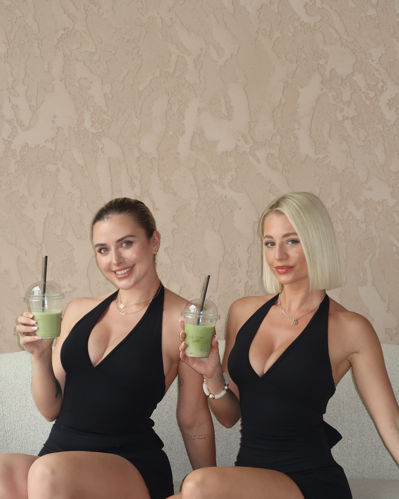 Two guests with matcha drinks against a damask backdrop