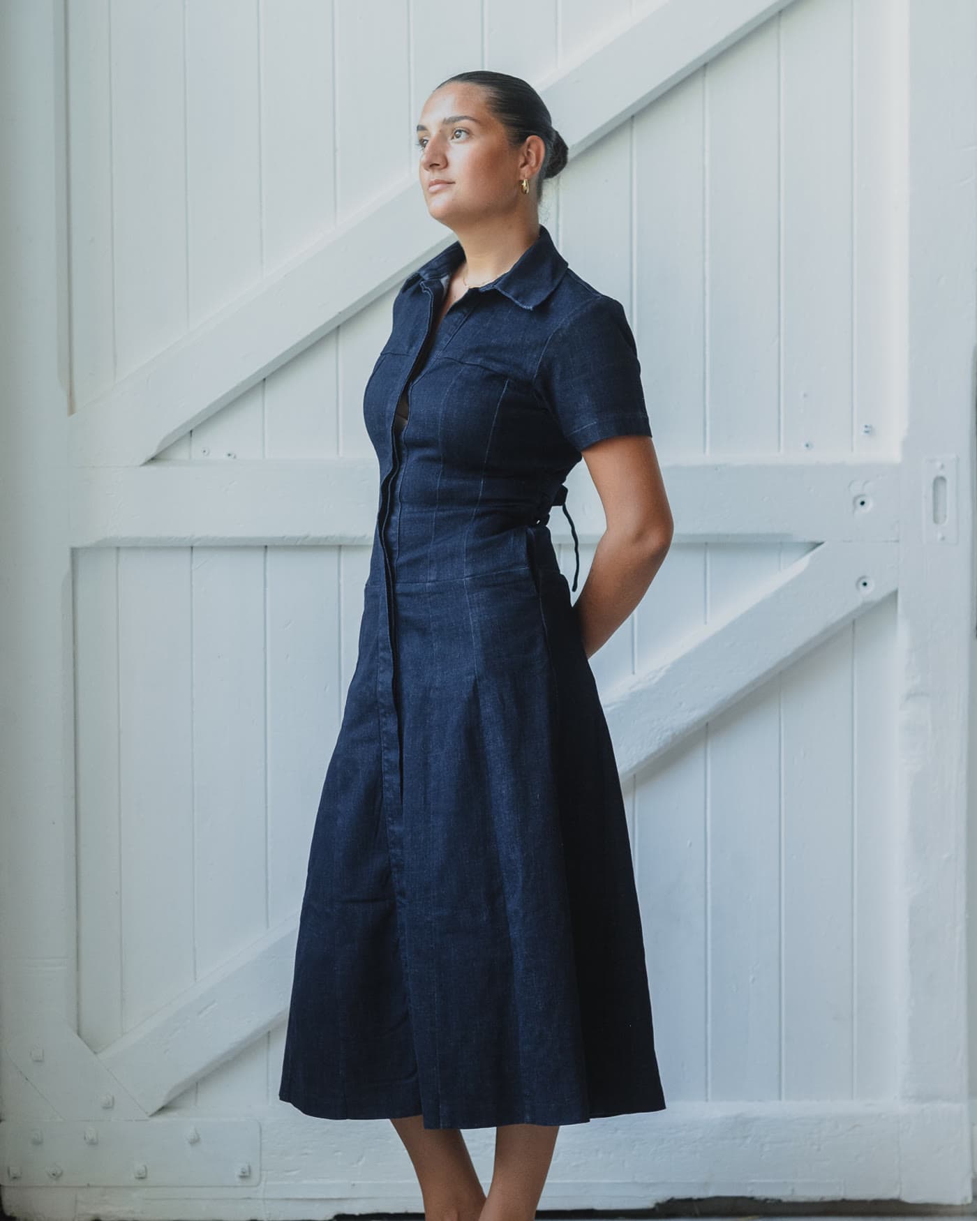 Denim shirt dress photographed front on against white timber doors