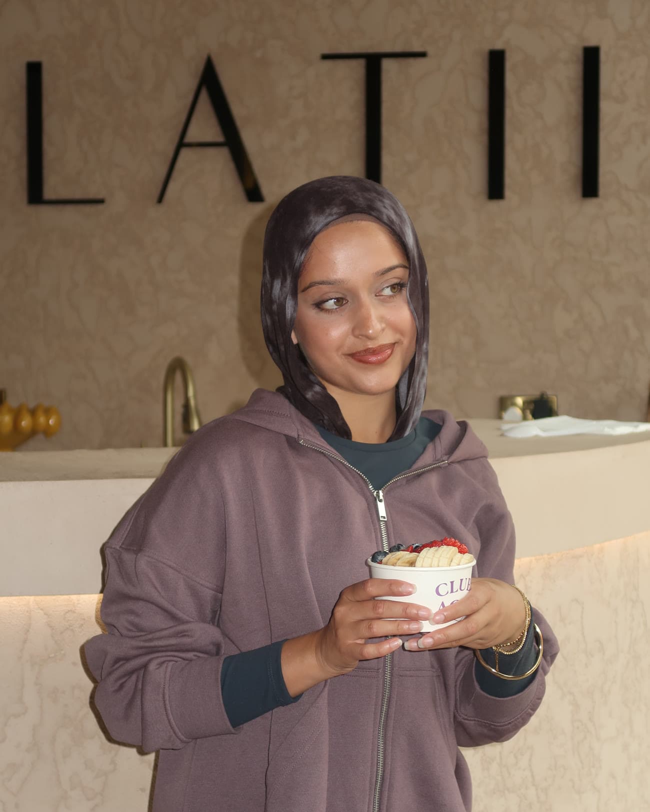 Guest with an açaí bowl beneath the BILATIS lettering
